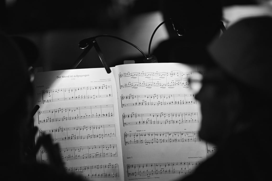 Black and white photo of sheet music titled "Der Mond ist aufgegangen" illuminated by small lamps in a dark setting